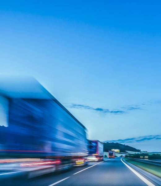 Background photograph of a highway, trucks on a highway, motion blur, light trails. Evening or night shot of trucks doing transportation